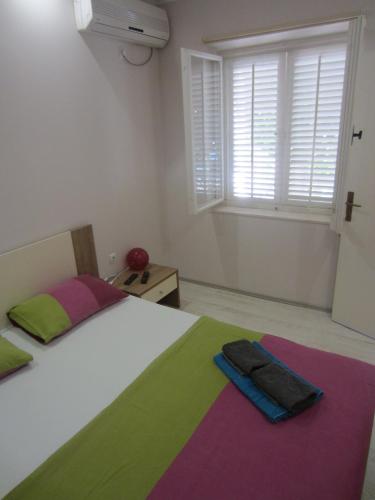 a bedroom with a bed with colorful sheets and a window at Apartments Morgen in Brna