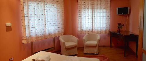 a bedroom with two chairs and a bed and two windows at Casa Del Sole in Soverato Marina