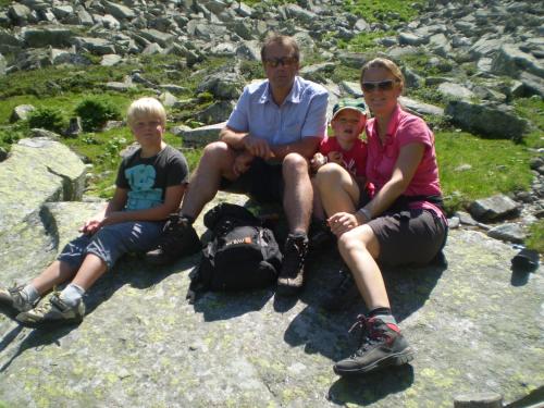 a man and two children sitting on a rock at Smaragdhotel Tauernblick in Bramberg am Wildkogel