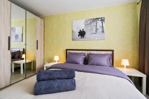 1 dormitorio con 1 cama grande con almohadas moradas en Lux Apartments, en Moscú