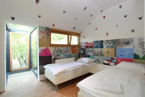 2 camas en una habitación con graffiti en las paredes en MCC Hostel en Celje