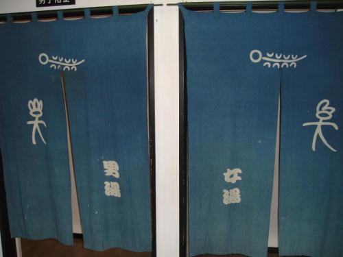 a pair of blue curtains with asian writing on them at Ryokan Kamomeso in Sado