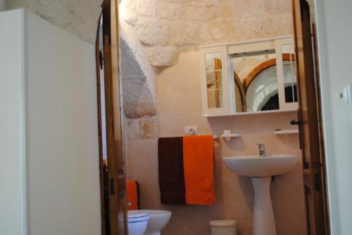 a bathroom with a sink and a toilet and a mirror at Trullo Pietraluna in Martina Franca