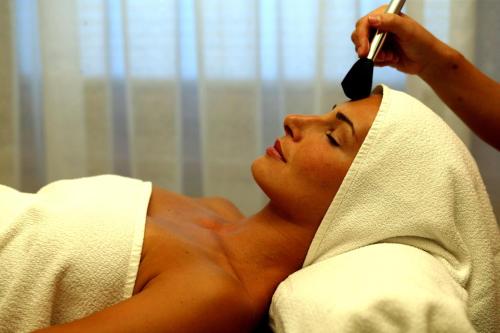 a woman laying in a bed getting her hair brushed at Smaragdhotel Tauernblick in Bramberg am Wildkogel