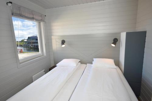 two beds in a small room with a window at Lankanholmen in Andenes