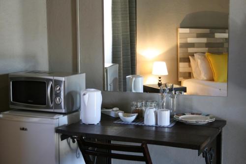a room with a table with a microwave and a bed at Lallapanzi Country Stay in Ermelo