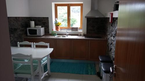 a kitchen with a table and a sink and a window at Casa da Ribeira in São Vicente