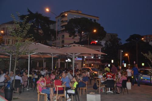 una multitud de personas sentadas en sillas en un restaurante al aire libre en Jolly City Center Hotel, en Tirana