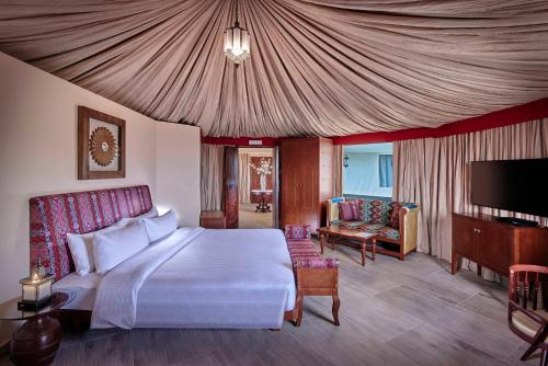 a bedroom with a bed and a tv and a couch at Dunes by Al Nahda in Labījah