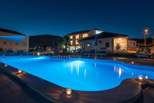 een groot zwembad dat 's nachts verlicht wordt bij Porto Samaria holiday resort in Trogir