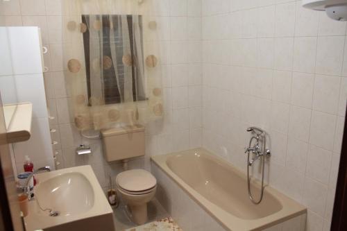 a bathroom with a tub and a toilet and a sink at Apartmani Peko in Pag