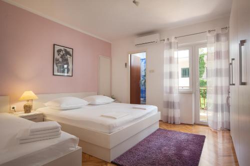 a white bedroom with two beds and a purple rug at Guest House Damir in Makarska
