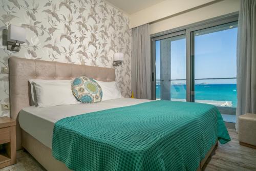 een slaapkamer met een bed met een groene deken en een raam bij Denise Beach Hotel in Laganas