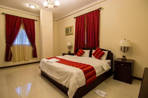 a bedroom with a large bed with red curtains at Shaza Al Khamis شذا الخميس in Khamis Mushayt