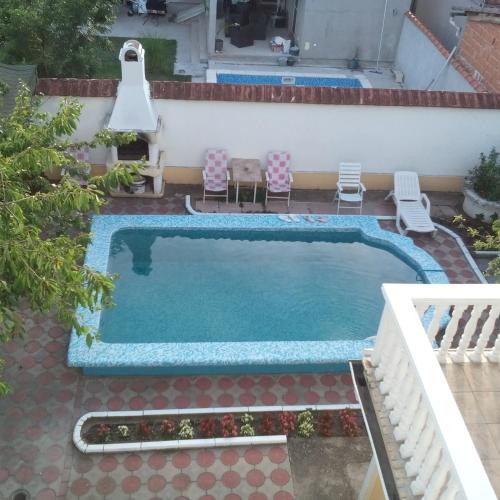 a swimming pool in a backyard with two chairs and a swimming pool at Ćane Rooms in Bela Crkva