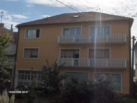 a large yellow building with a balcony on it at Ćane Rooms in Bela Crkva