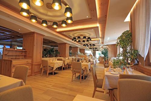 a dining room with tables and chairs in a restaurant at Hotel Cesa Tyrol in Canazei