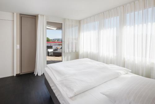 sypialnia z białym łóżkiem i oknem w obiekcie achesa homes w mieście Opfikon