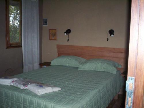 1 dormitorio con 1 cama verde y 2 almohadas en Verde Niña Casas Serranas en Cortaderas