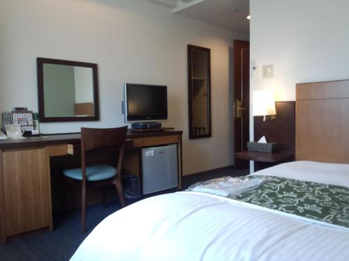東広島市にある東広島グリーンホテルモーリスのベッド、デスク、コンピュータが備わるホテルルームです。