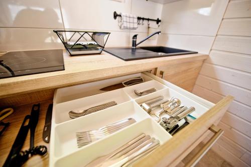 a kitchen with a sink and a drawer with utensils at Domki Na Brackiej in Pobierowo