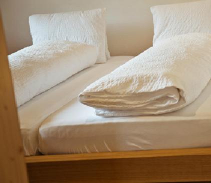 - un lit avec des draps et des oreillers blancs dans l'établissement Apartment Alpina, à Brigels