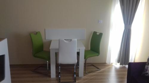 a table and two green chairs in a room at Apartments Delić in Nikšić