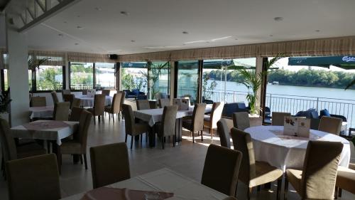 ein Restaurant mit Tischen und Stühlen und Blick auf das Wasser in der Unterkunft B&B Posejdon in Sremska Mitrovica