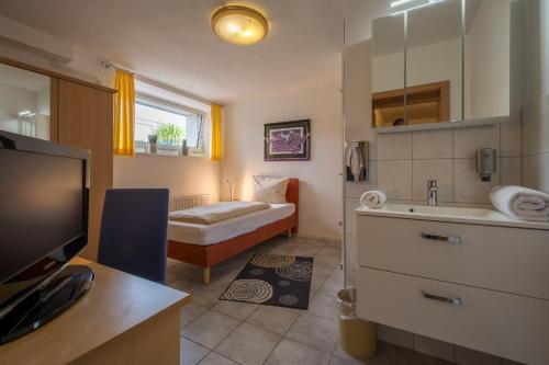 a bathroom with a bed and a sink and a television at Pension Margarethe in Biedenkopf