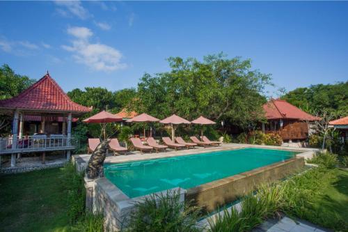 a swimming pool with chairs and umbrellas at Darsan Lembongan Boutique Cottage in Nusa Lembongan