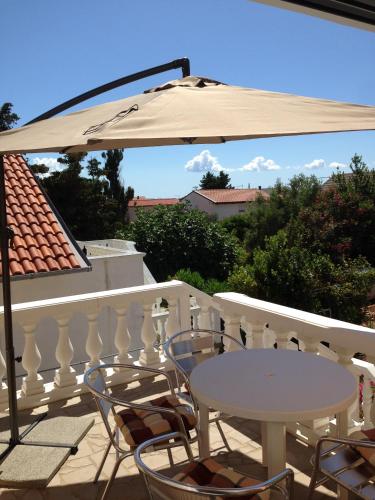 a white table and chairs on a balcony with an umbrella at Apartment Vujic in Vir