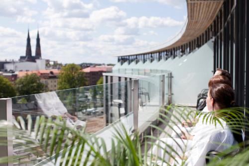 a woman sitting on a balcony looking out at the city at Radisson Blu Hotel Uppsala in Uppsala