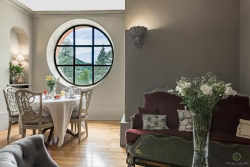 a living room with a table and a round window at Hôtel Restaurant Spa Le Sauvage in Besançon
