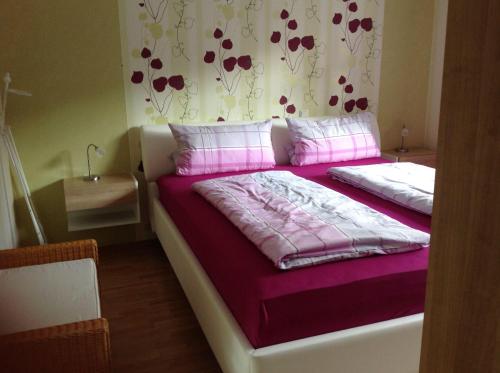a bedroom with a bed with purple sheets and pink pillows at Ferienwohnung-Abendroete in Lüdersburg
