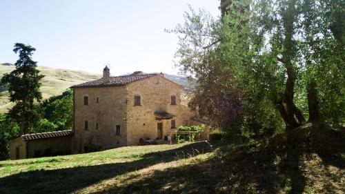 an old stone house on a hill with trees at Agriturismo La Quiete in Volterra