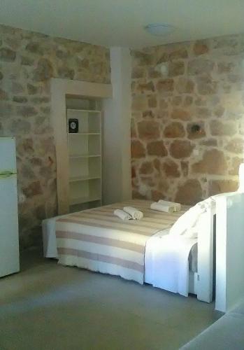 a bedroom with a bed and a stone wall at Apartment Vidačak in Tisno