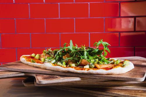 a pizza sitting on top of a wooden cutting board at Mövenpick Hotel Zürich-Regensdorf in Regensdorf