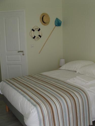 a bed with a striped blanket and a hat on the wall at Les Chambres de Jeannette in Marseille