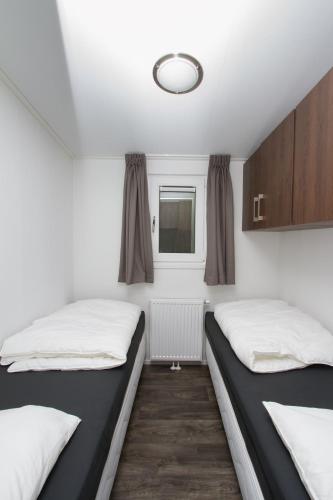 two beds in a room with white walls and a window at Vakantiecentrum De Ullingse Bergen in Sint Anthonis
