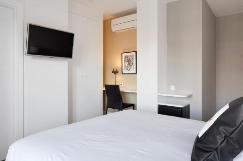 a bedroom with a white bed with a flat screen tv at Hotel Flysch in Zumaia
