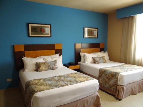 two beds in a hotel room with blue walls at Metro Hotel Panama in Panama City