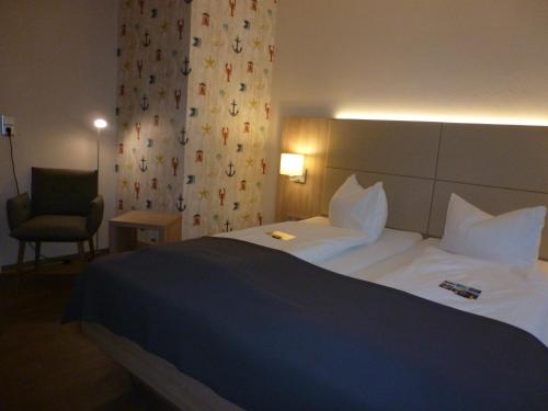una habitación de hotel con una cama grande y una silla en Hotel das Möwenstübchen en Wremen