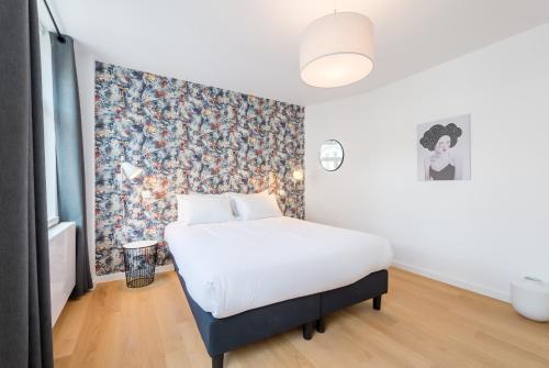 Schlafzimmer mit einem Bett mit Blumentapete in der Unterkunft Smartflats - Toison d'Or in Brüssel