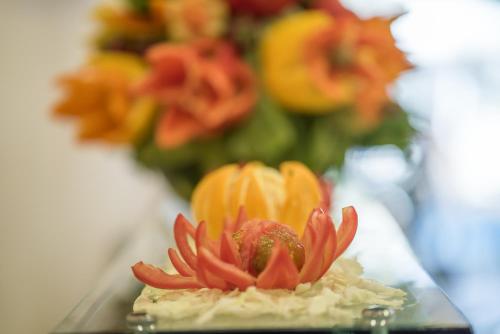 a small red flower on a glass plate with flowers at Denise Beach Hotel in Laganas