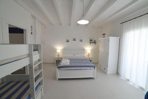 um quarto branco com uma cama e 2 beliches em Latino Rent Room B&B vista mare em Porto Cesareo