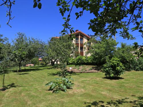 una casa en medio de un patio con árboles en Apartamentos Rurales L'Arquera en Llanes