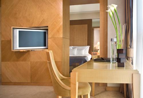 a room with a desk and a tv and a bedroom at Melia Athens in Athens