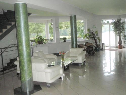 a lobby with white chairs and a table and columns at Hotel Nidzki in Ruciane-Nida