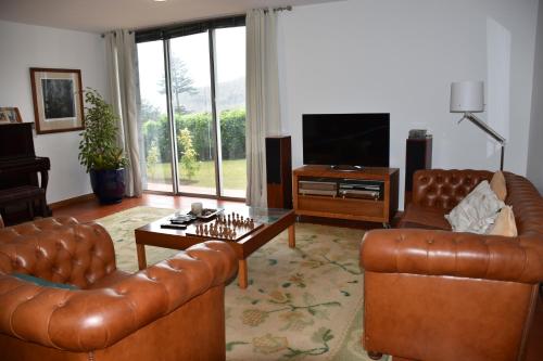a living room with two leather couches and a television at Caloura Camellia House in Caloura