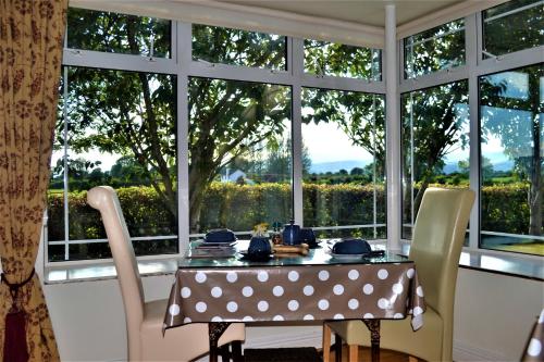 uma sala de jantar com uma mesa e cadeiras e uma janela em Annaswood B&B em Cahir